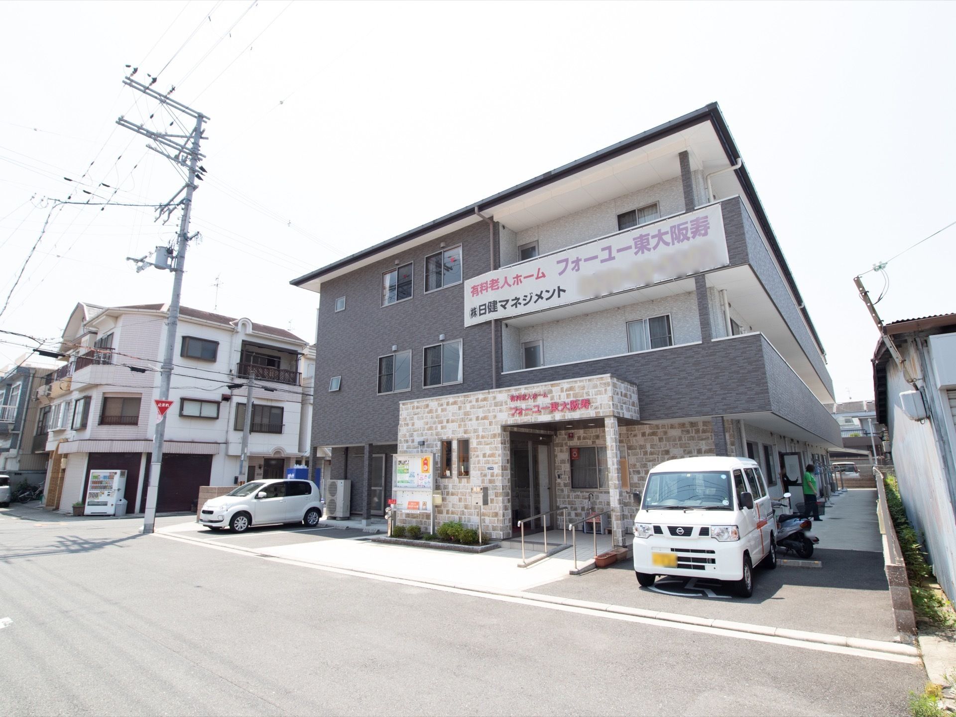 施設は住宅街の角地に建っている。施設前は駐車スペースが確保されており、送迎用の車両が停められている。