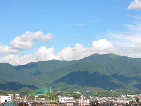 草木が茂っているなだらかな山地の手前に広がる市街地