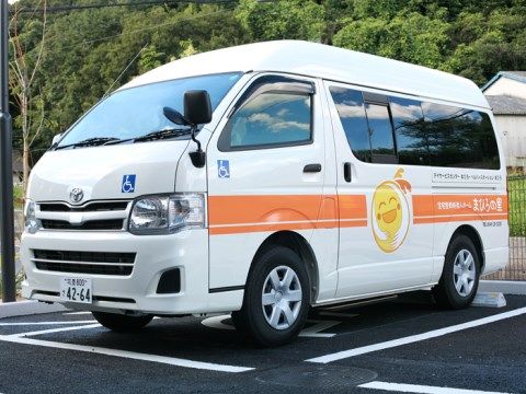 駐車場に停められている施設名称を塗装した白い大型車両