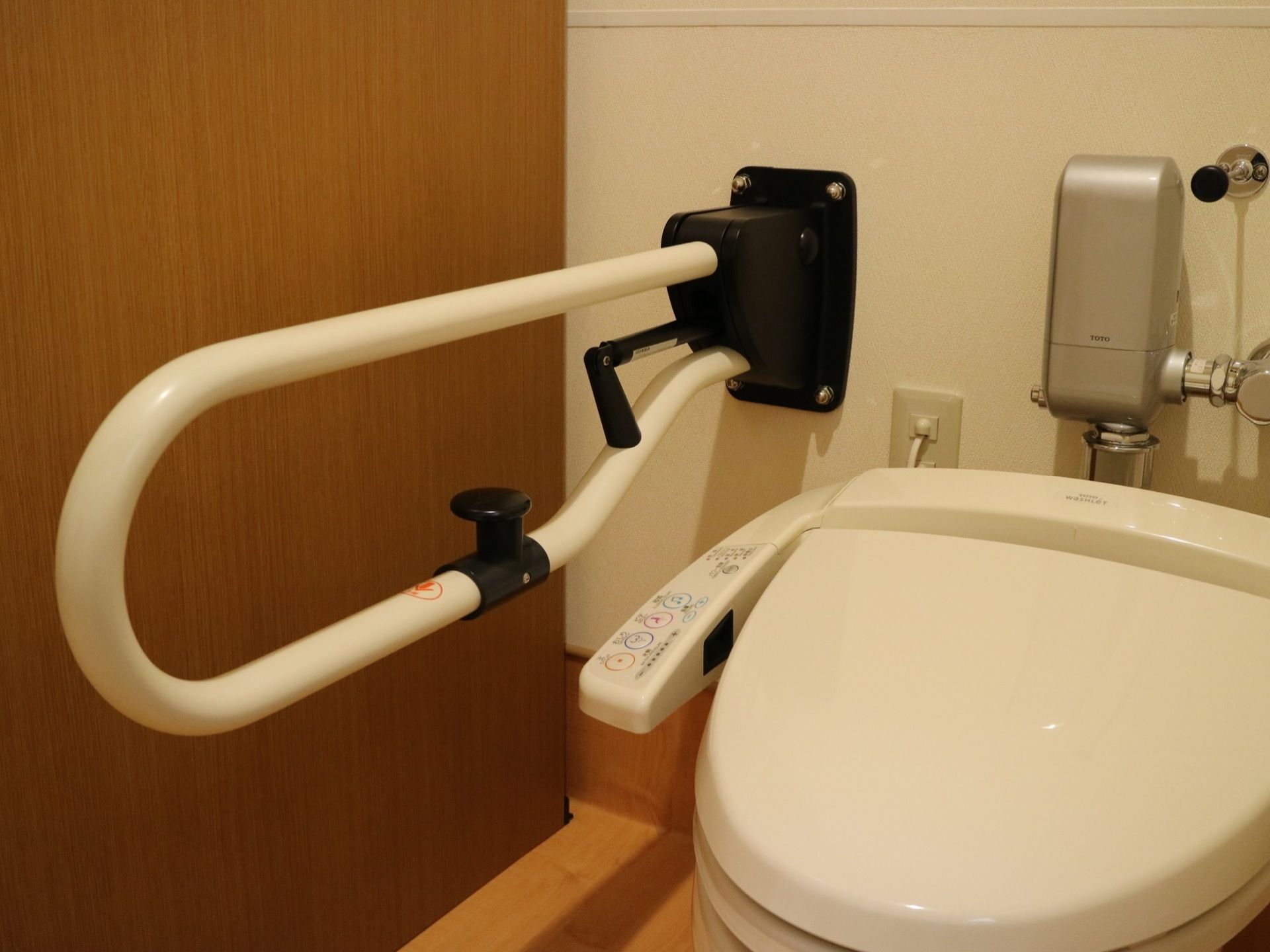 トイレは、水タンクがない省スペースタイプの便器である。便座の操作パネルの横に、可動式の手すりが設置されている。