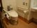 洗面台の左側の少し奥まったスペースにトイレが設置されている。便器の両側には手すりがあり、壁には呼び出しボタンがついている。