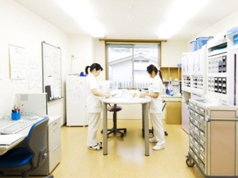 テーブルに向って書類を確認している白衣のスタッフ２名