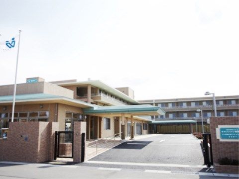 施設外観。レンガ造りの門に旗が掲げられ、エントランスには大きな屋根がある。