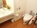 壁面が白く、トイレの便座、洗面台も白で統一されている。洗面器側に花が飾ってある。緊急時に職員を呼び出すことが出来るブザーが壁についている。