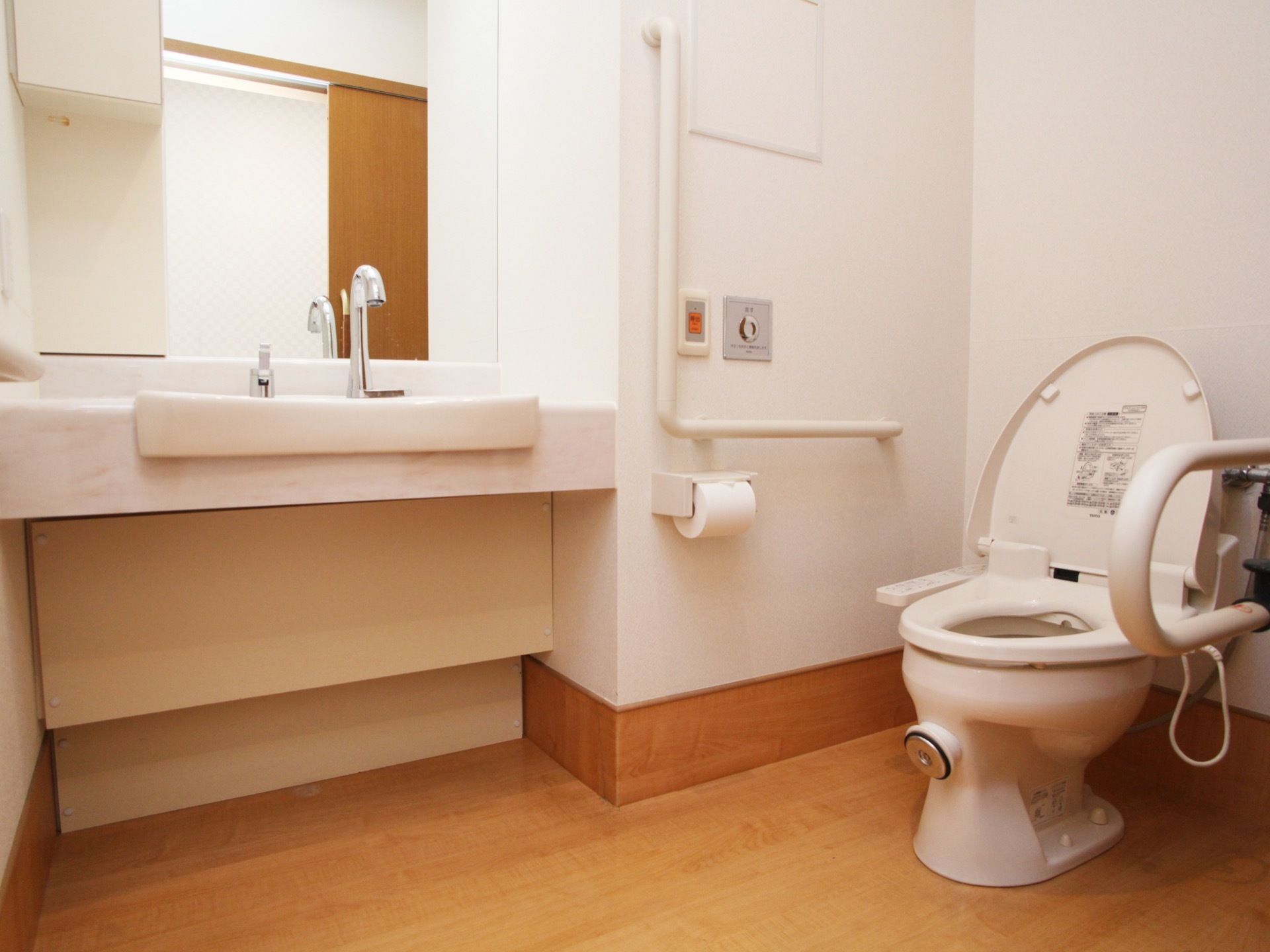 車椅子のまま入ることができるトイレには、掴まることができるいくつかの手すりと洗面台が設けられている。