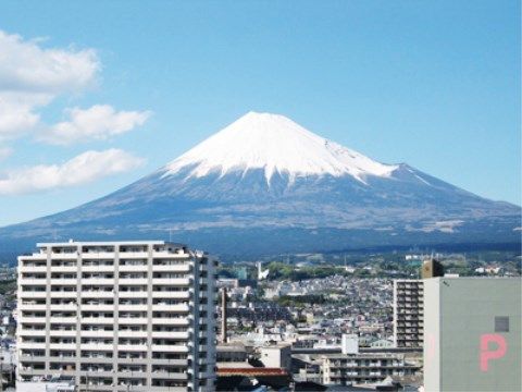 よく晴れた青空の下、屋上から見える街並みと遠くの山