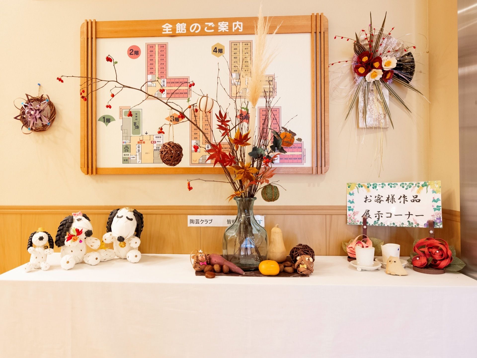 季節の花を使ったアレンジや、リボン編みの人形、蔓を編んで作る籠やリースなど、さまざまな作品が飾られている。