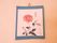 バラが描かれており、青い台紙に張ってある。一つは満開、二つは蕾の絵で茎や葉は黒で塗ってある。右下に名前とハンコが押されている。