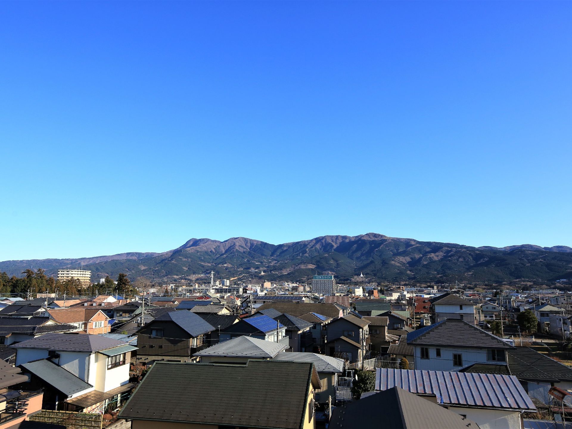 屋上から見える風景。周りは住宅街になっており、高い建物がないので、周囲を広く見渡すことができる。遠くには山脈が連なっている。