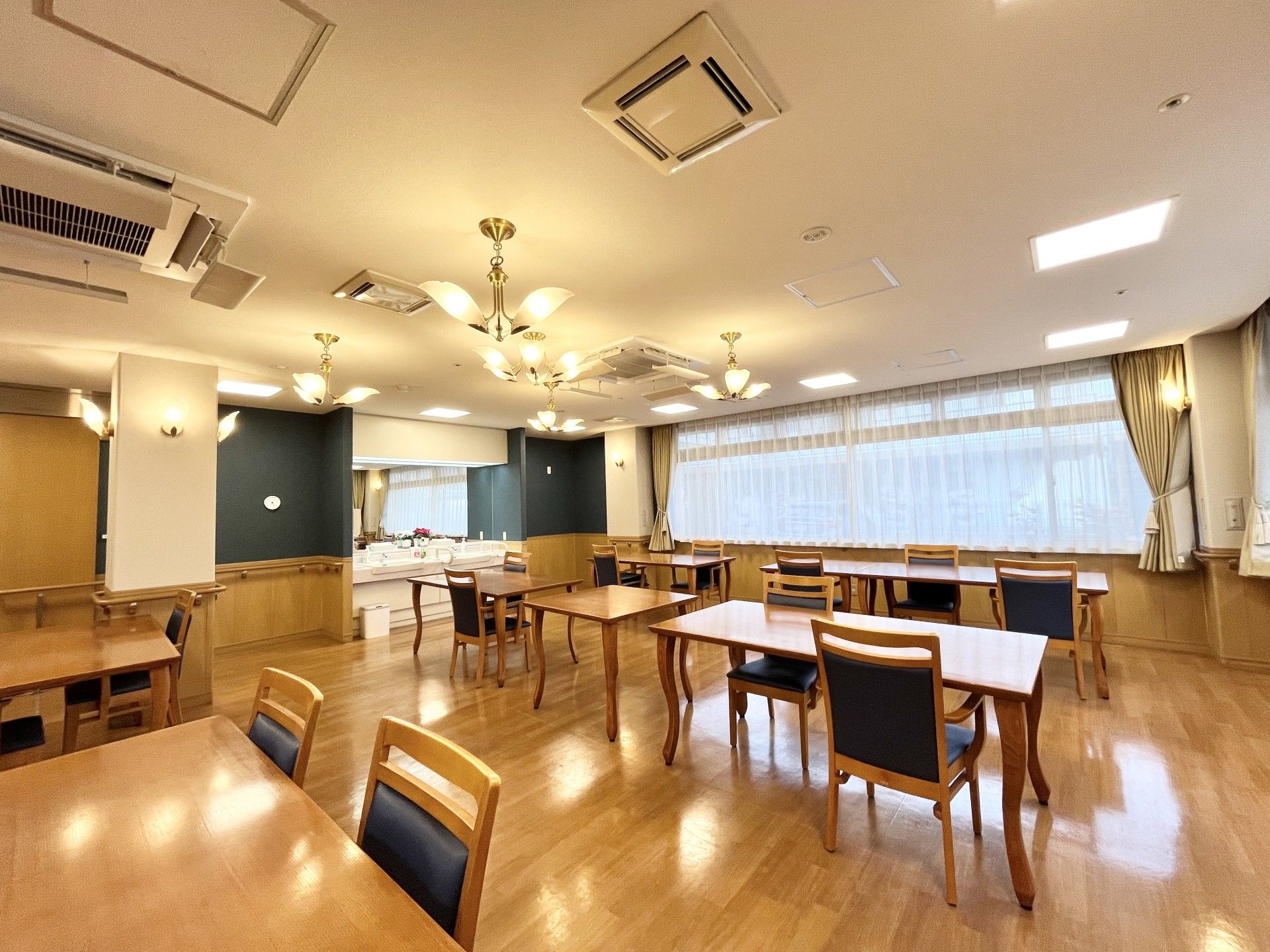 大面鏡がある洗面台で、手すりが左右についている。自動販売機が横に置いてある。ダイニングテーブルと椅子が置いてある。