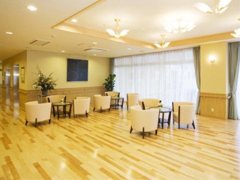 大きな窓のある明るく開放的なエントランスホールである。天井にはデザイン性のある照明が複数設置されている。