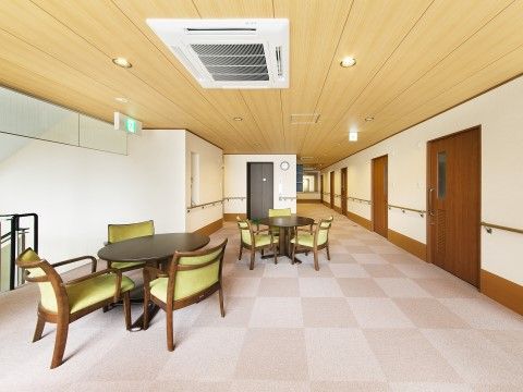 濃いブラウンの丸テーブルと椅子が置かれている。壁には手すりがついており、車椅子での移動も楽に行えるスペースも確保している。