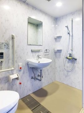 トイレ内に用意されたシャワースペース。洗面台の横に立って使用することができるシャワーが備え付けられている。