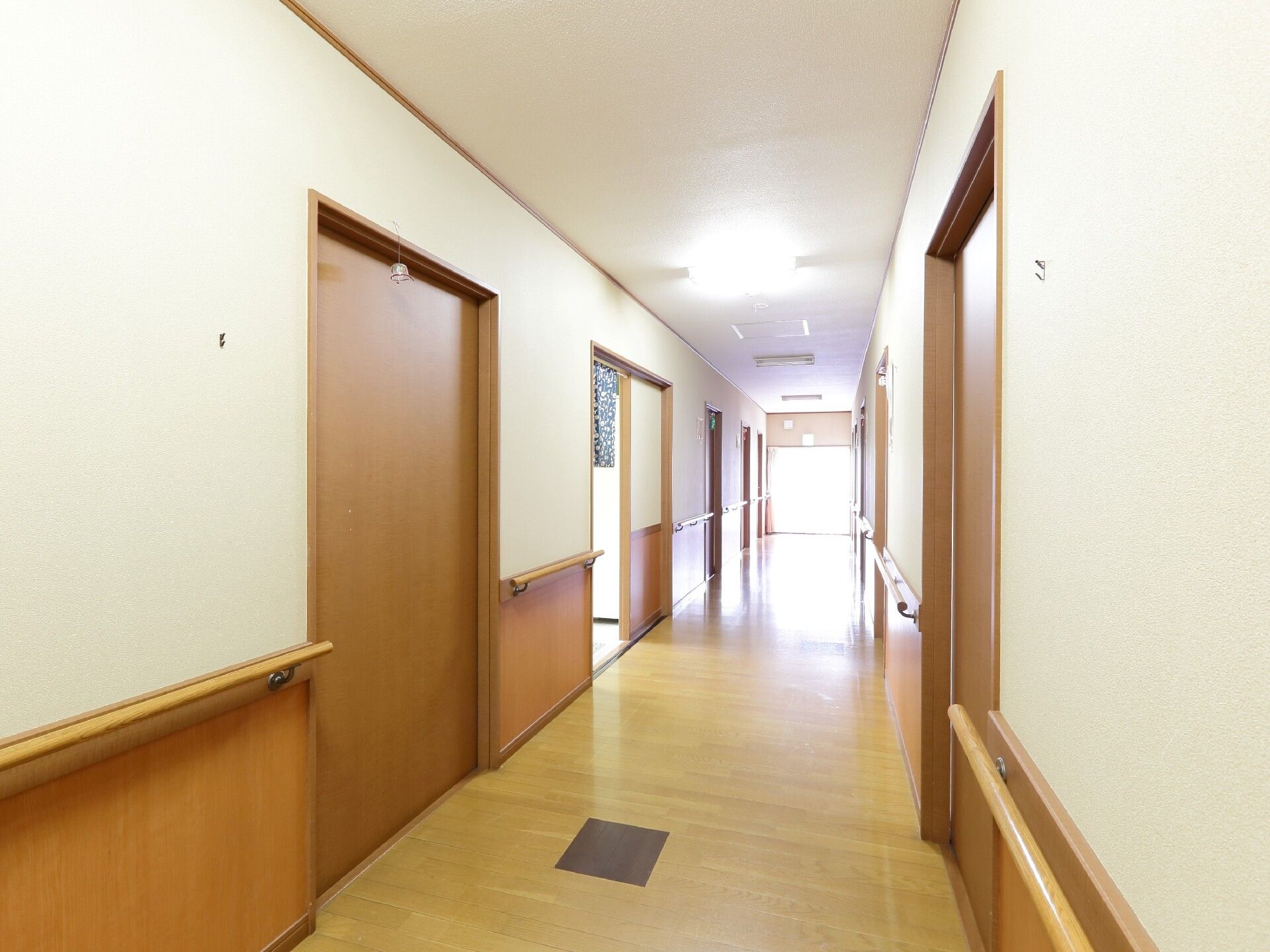 壁に手すりのついた廊下。部屋にはスライド式のドアが付いている。