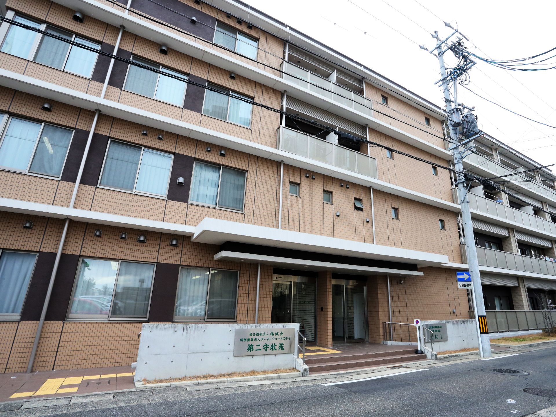 建物は4階建ての建物である。壁の色はオレンジ色となっている。出入口の上には白い屋根が設置されている。