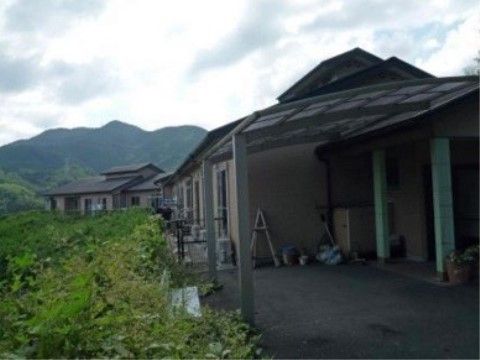 山を望む施設の敷地内に設けられた、屋根付きの駐車スペース