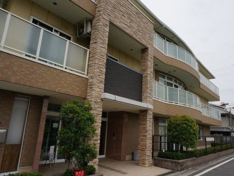 ゲード部分に細割のブロックがあしらわれ、バルコニーは流動的なデザインが用いられた、３階建てのモダンな施設の外観