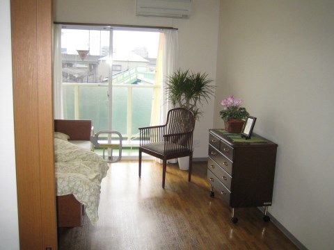 落ち着いた色調でまとめられた居室には、ベッドとキャスター付きの収納家具、デザイン性の高い椅子が置かれている。