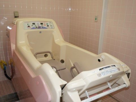 ピンクのタイル張りの壁によく合う、同じくピンクの介護用浴槽は、座ったままの姿勢で入浴できるタイプだ。