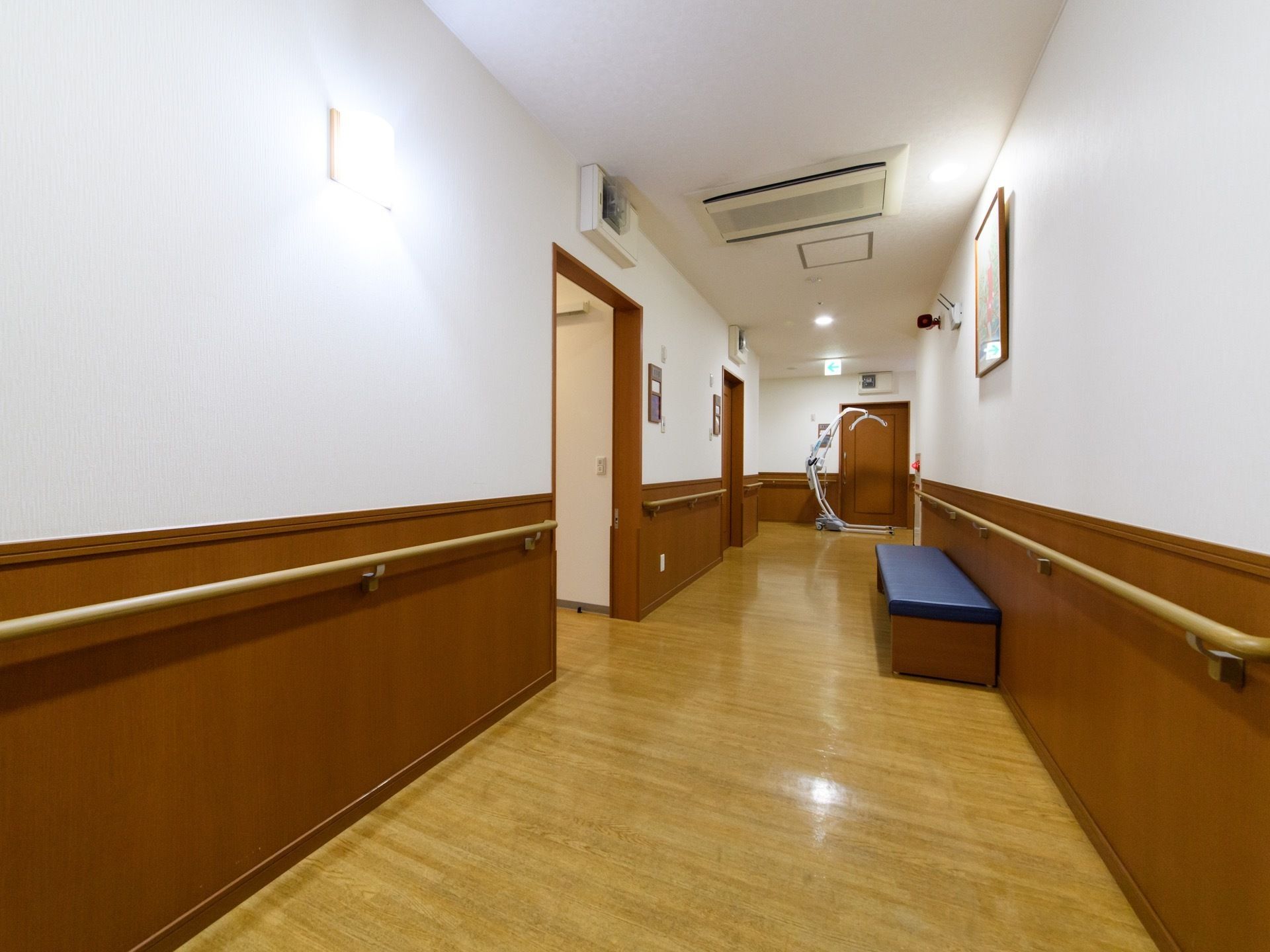 木目調のフローリングに壁は床から腰高までは濃いめのベージュ色でそれより上は天井も白色でまとめられている。壁には手すりが続いている。