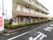 施設は３階建てである。２階３階にはベランダが続いている。１階には建物にそって低木の植栽帯があり、黒いフェンスで囲われている。