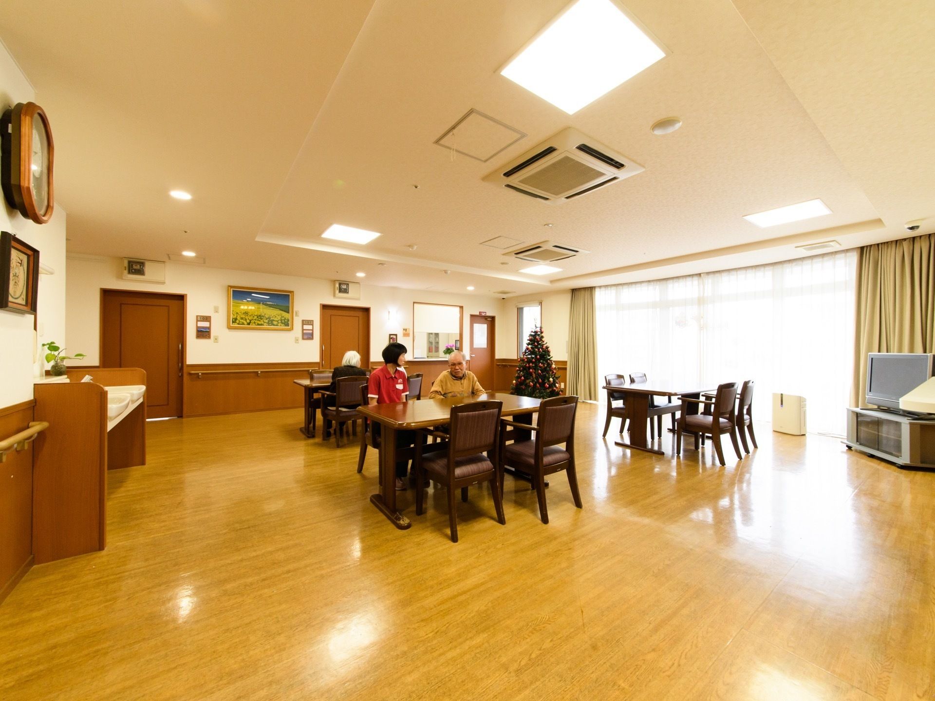 ダイニングテーブルにセットされた椅子に座って話す、スタッフと入居者