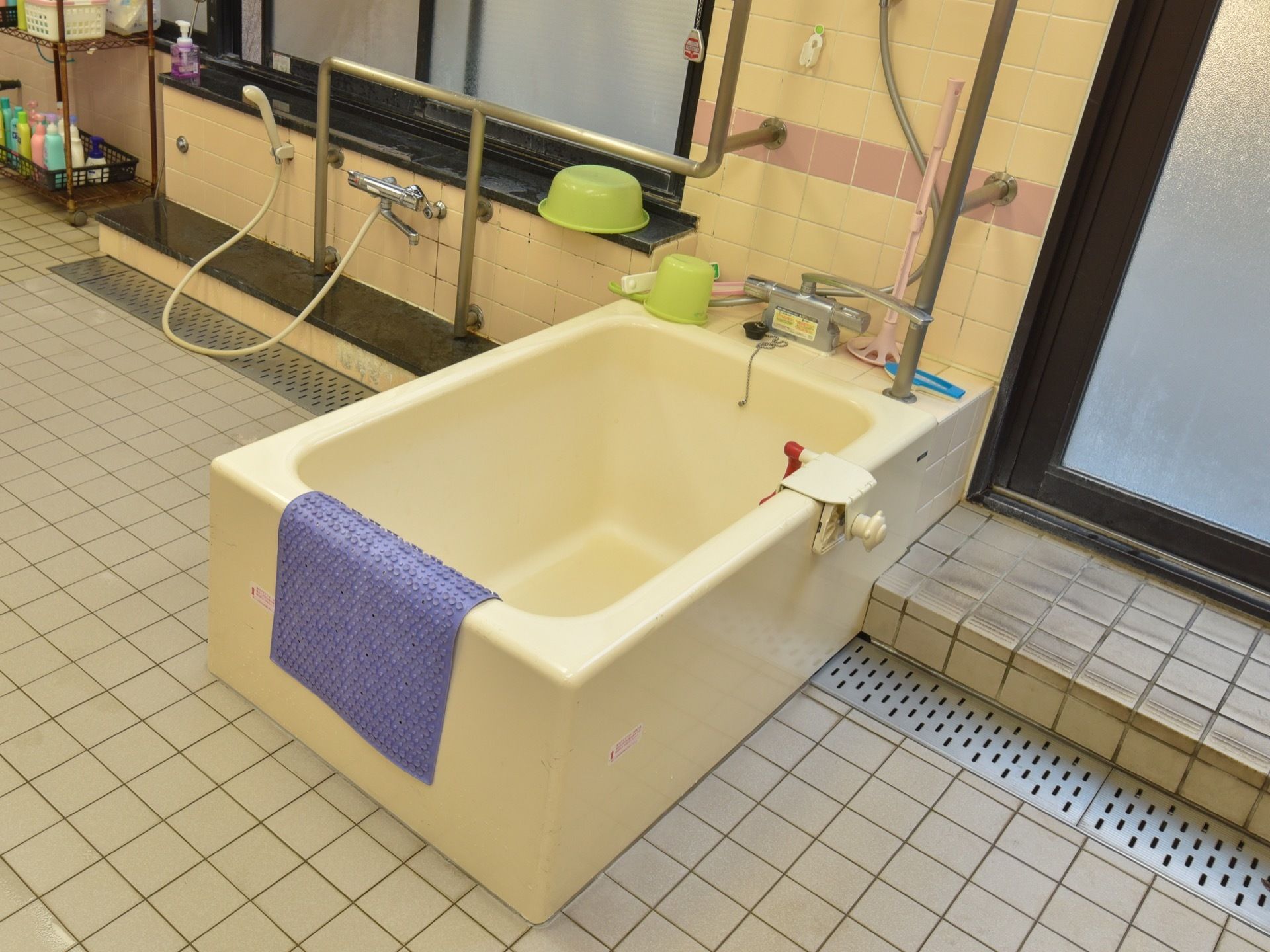 共同浴室に設置している１人用の浴槽である。隣には洗い場を設け、黒枠の窓がある。壁には、手すりを設置している。