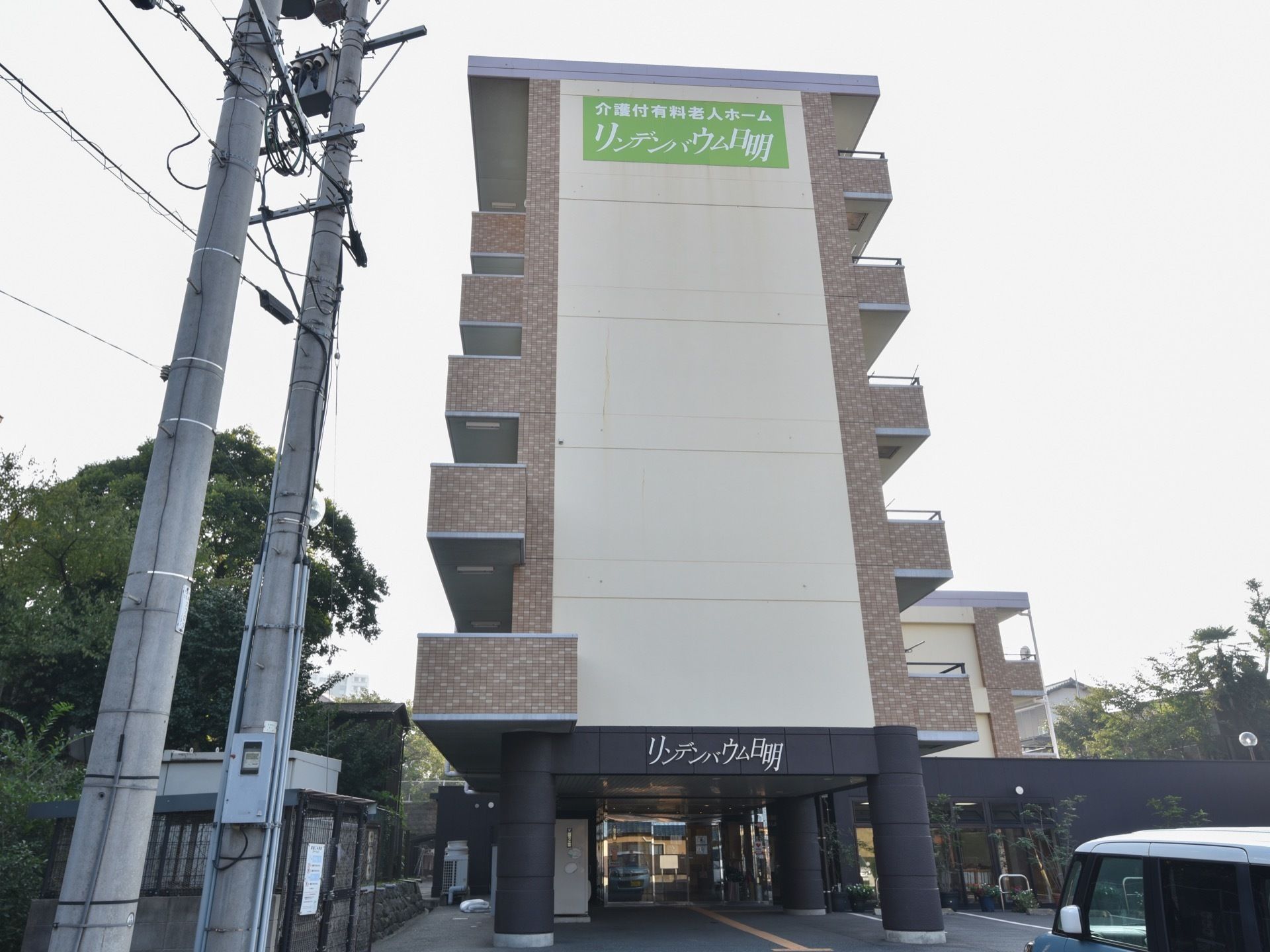 玄関正面の外観である。６階建ての建物で、側面の一番上の部分に黄緑色の背景に白文字で描かれた施設名を掲げている。