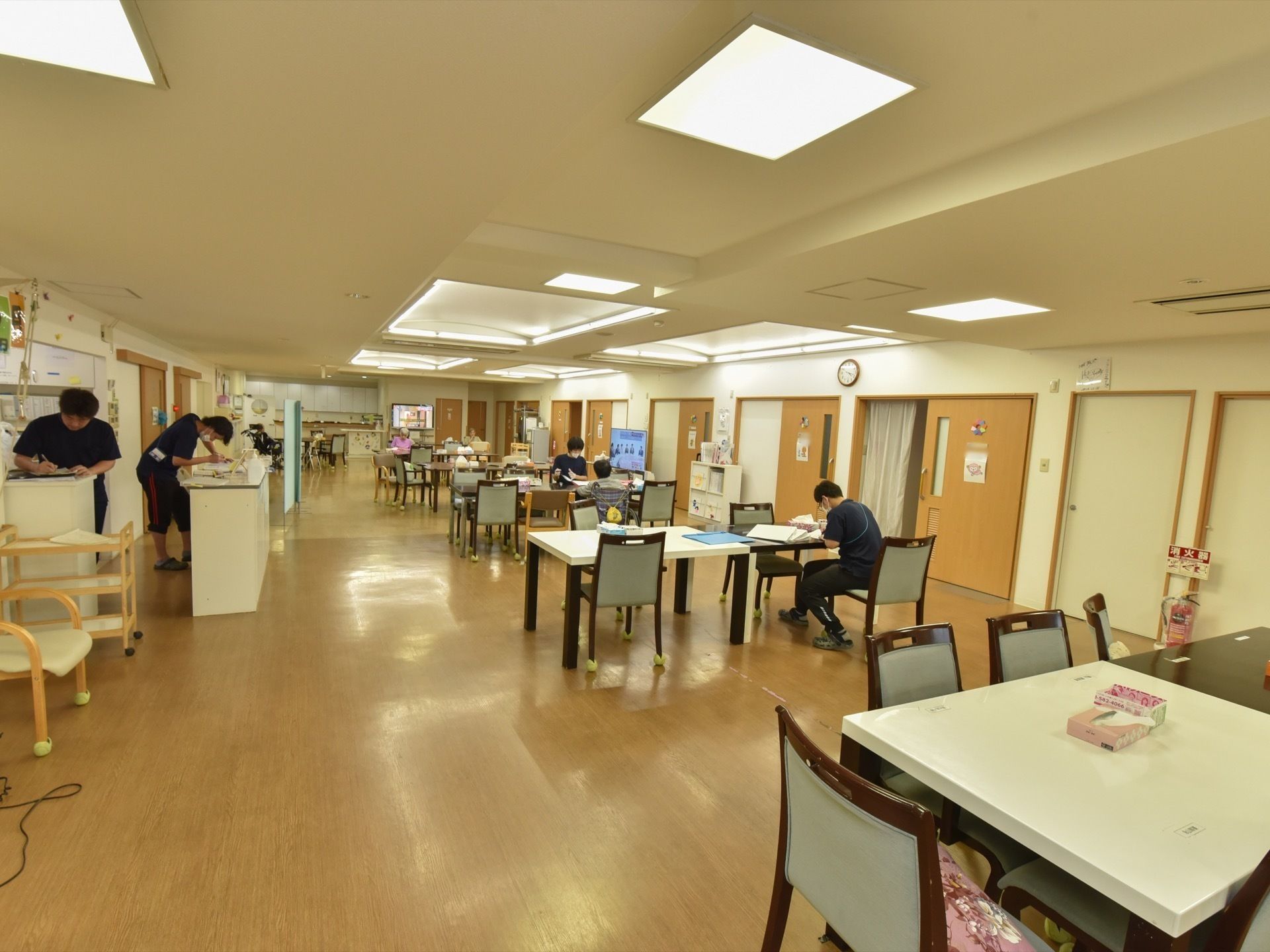 広々としたダイニングルームで、事務作業などをするスタッフと、打ち合わせや休憩をする入居者