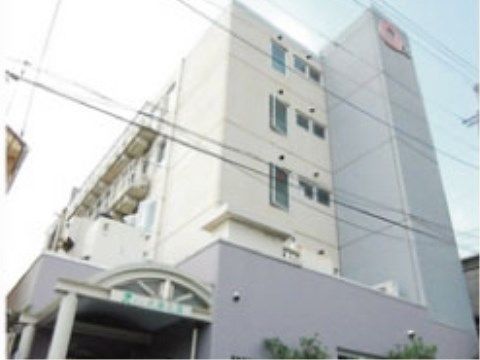 エントランスに屋根の付いた建物。周りに木が植えられている。