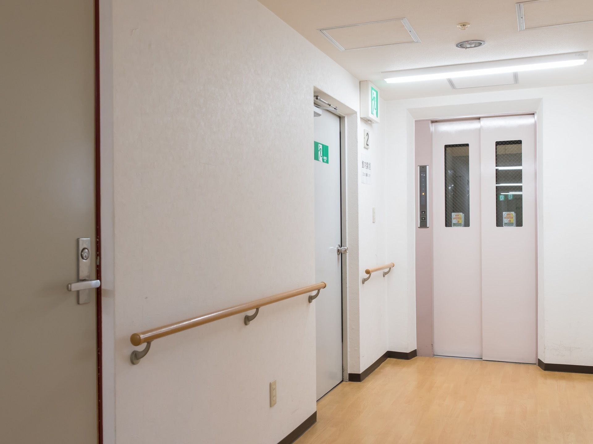 通路の突き当たりにエレベーターがあり、その手前の左側に非常口の扉がある。壁には手すりが備わっている。