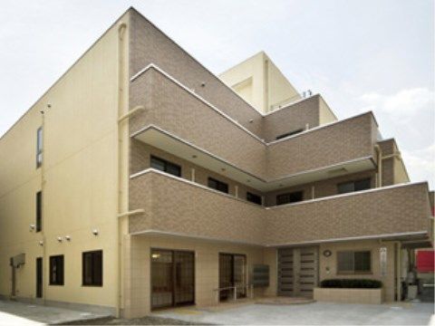 屋上付き３階建ての、ベージュとアイボリーの施設の外観