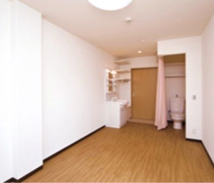 居室はゆとりある空間を確保している。トイレはカーテンで仕切られているので出入りにストレスがない。また洗面台には収納棚を設置している。
