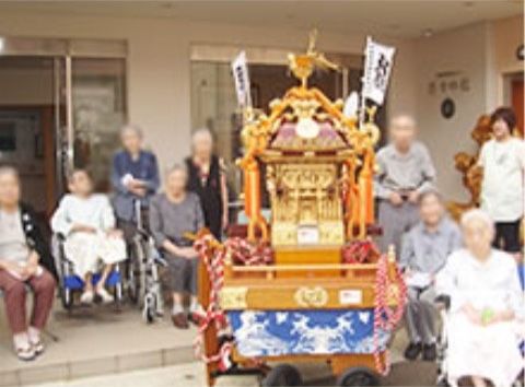 微笑む利用者と祭りの山車