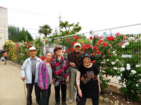色とりどりの花が咲く花壇の前で、笑顔で集合写真を撮る入居者様たちの外出の様子