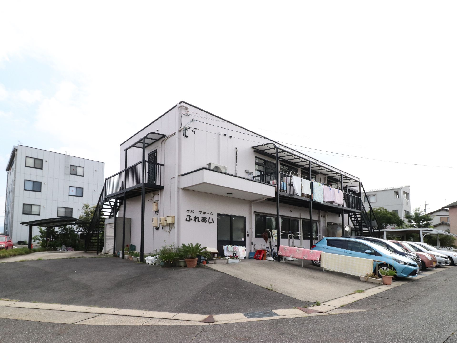 建物は2階建てになっている。左側には2階へ続く階段が付いている。駐車場は、建物前に複数台停められる。