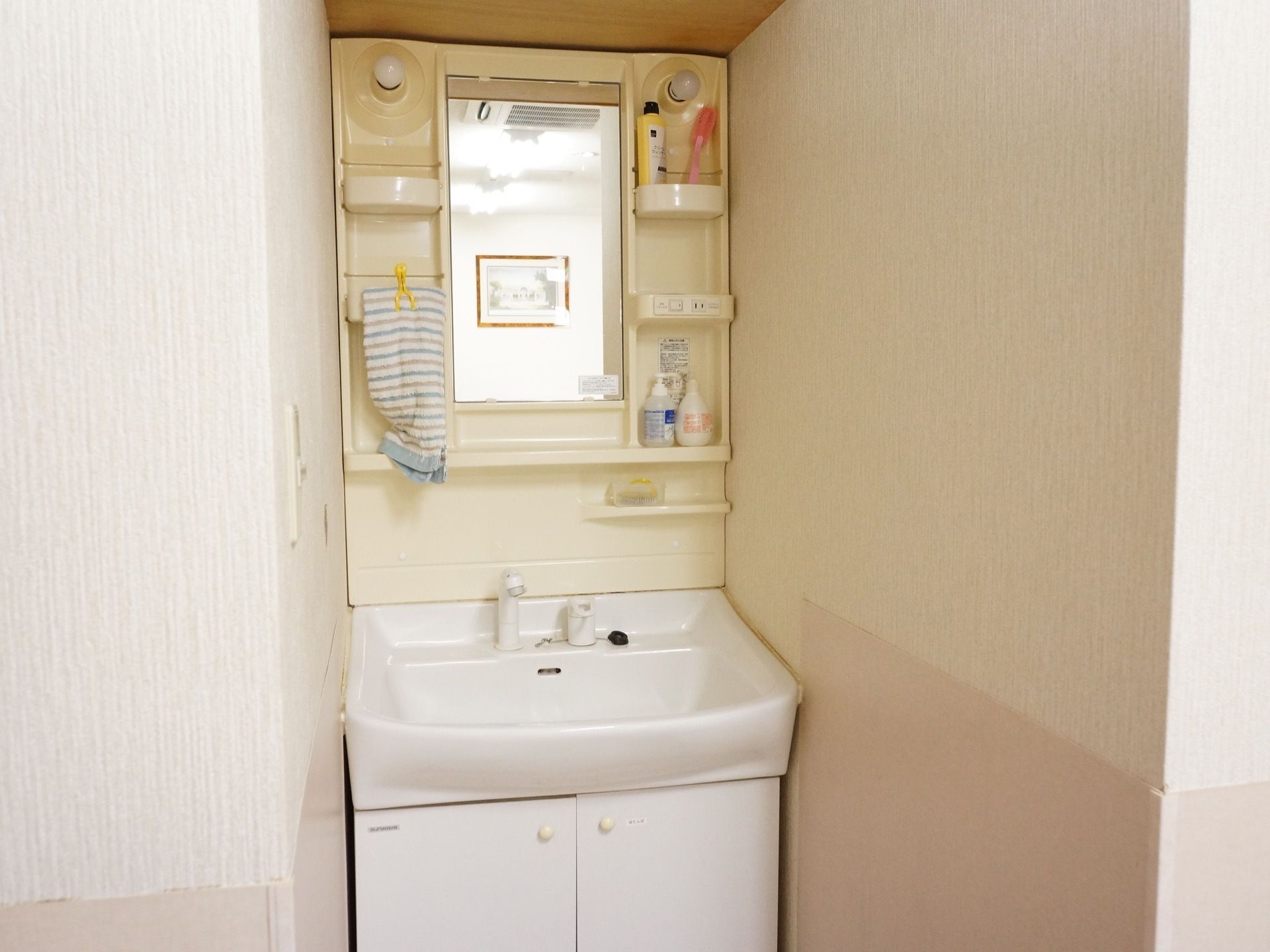 洗面台の正面の鏡の左右には棚が付いている。足元には扉付きの収納があり、洗面台まわりをすっきりと使うことができる。