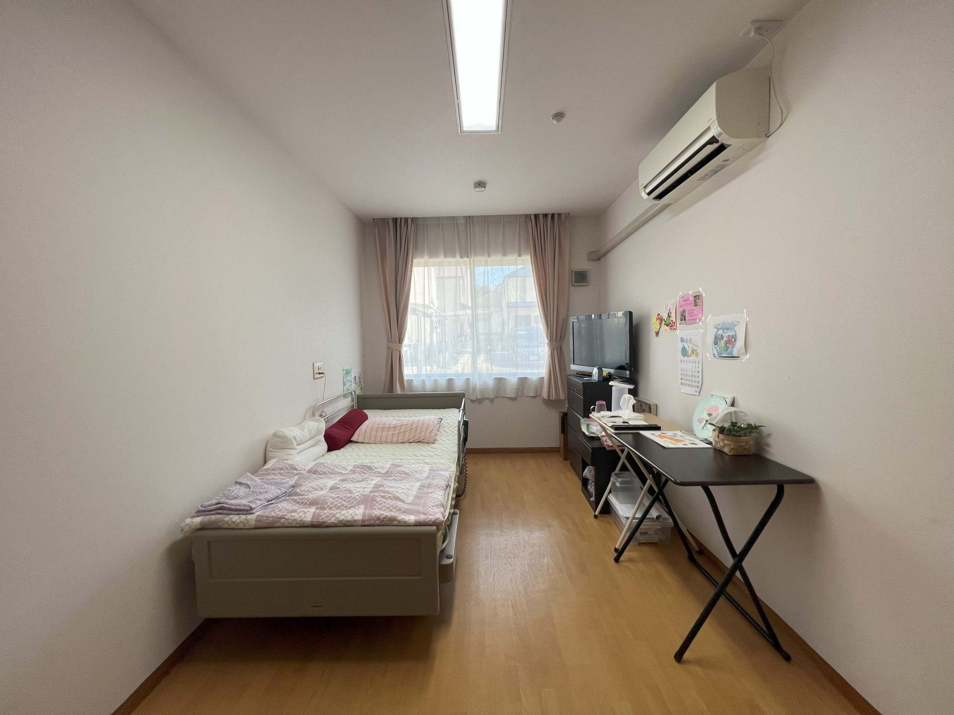 介護ベッドに腰かけてテレビを見ている入居者様がいる個室