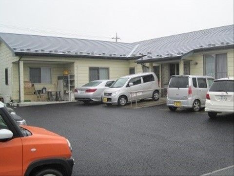 たくさんの車が停められる駐車場とスロープが付いた平屋建ての施設