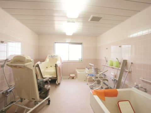 ゆったり広い浴室である。右の壁沿いには手前と奥に２つの浴槽があり、左の壁近くには座ったままでお風呂に入ることができる介護入浴設備がある。