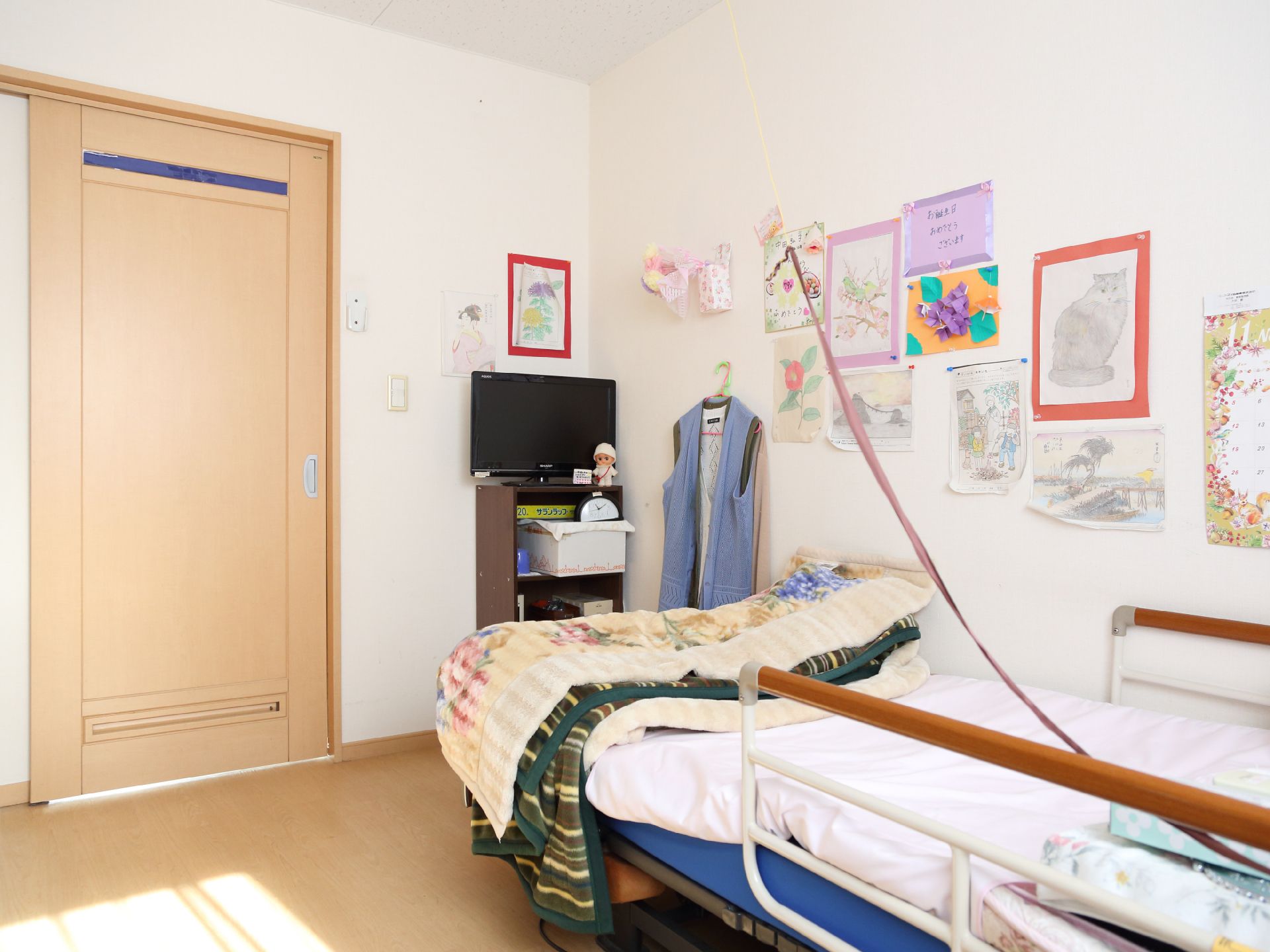 完全個室の居室である。床はフローリングになっており、扉は引き戸が採用されている。壁際に介護ベッドが置かれている。