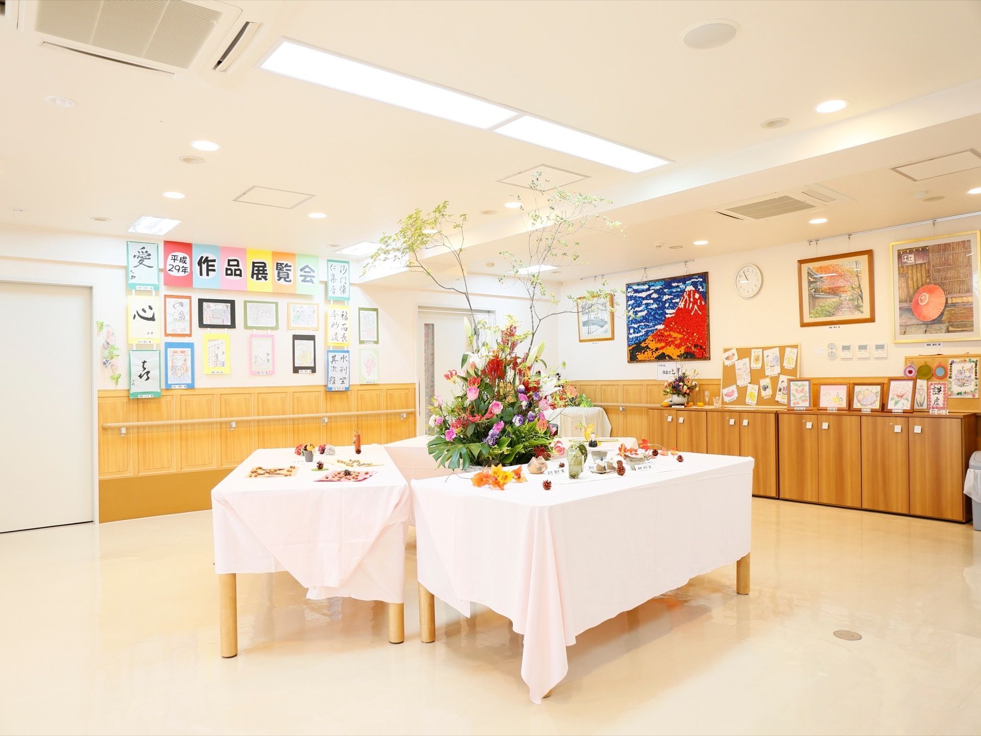 共有スペースの天井では照明がたくさんあって電気がついているので、部屋が明るくなっている。テーブルの上には大きな観葉植物が置かれている。