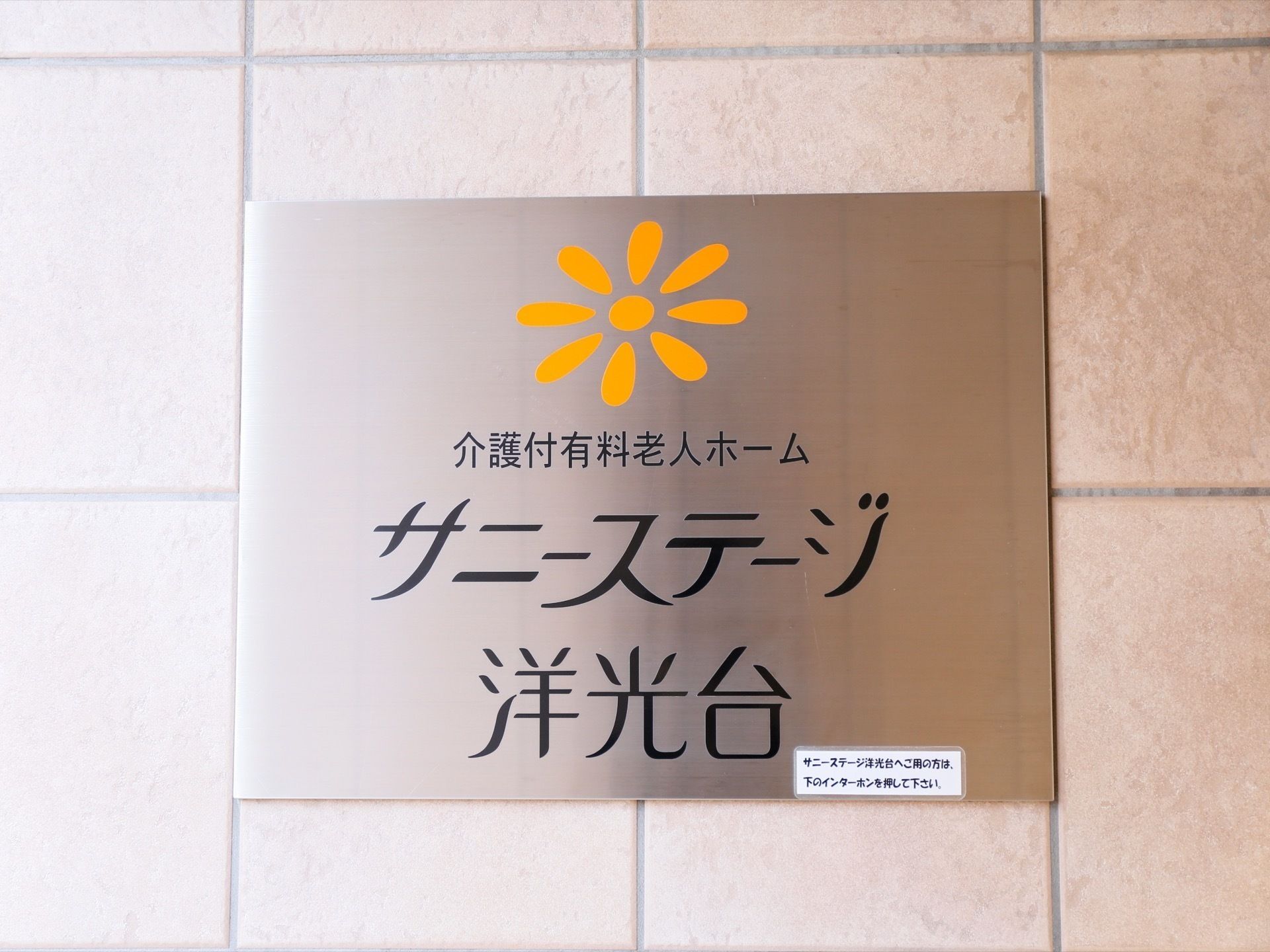 施設のマークと名前が大きく表示された銀色の四角い表札