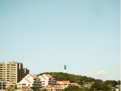 住宅地に囲まれ静かな環境に立地している。小高い丘の斜面に並ぶ住宅や、山の緑を遠くに眺めることができる。
