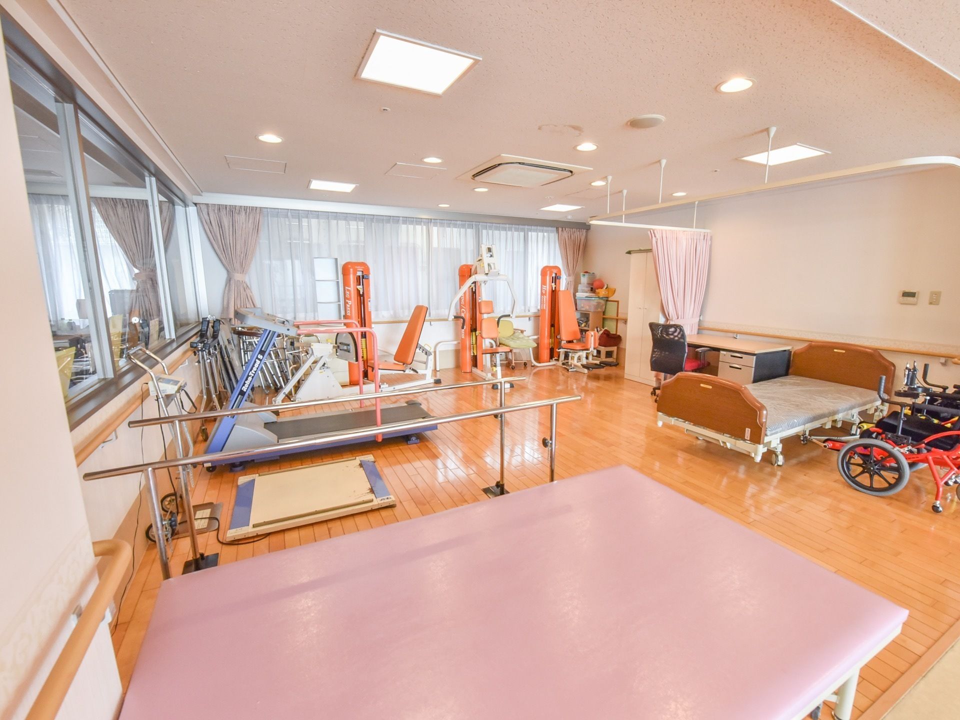 施設内には広々とした機能訓練室があり、平行棒やランニングマシンといった、さまざまな機器が置かれている。