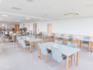 清潔感のある白い壁の食堂にはテーブルが並び、入居者様が気持ちよく食事を楽しめるように整備されている。