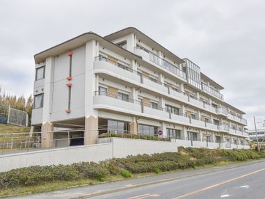 ４階建ての白い建物は、1階の部分が一部駐車場になっている。屋根付きの駐車場なので、天候を気にせず利用することが可能。