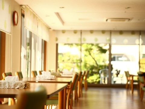 大きな窓にスクリーンカーテンがかかっている。テーブルセットがたくさん並んでいる。テーブル同士の間は広く余裕のある配置になっている。