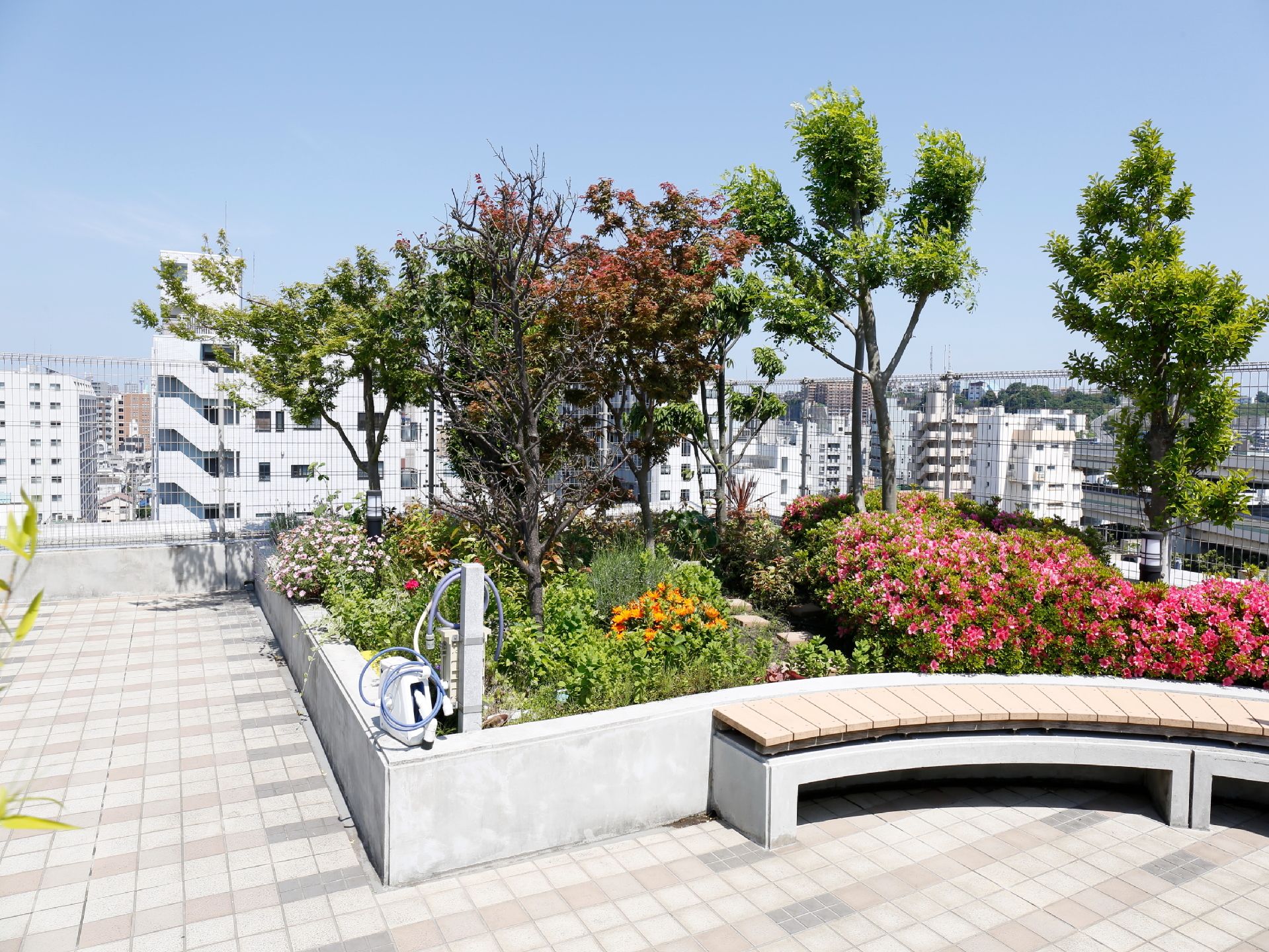庭木や花が植えられいる花壇の前にはアーチ形のベンチが設置されている。また、周りの街並みの風景が一望できる。