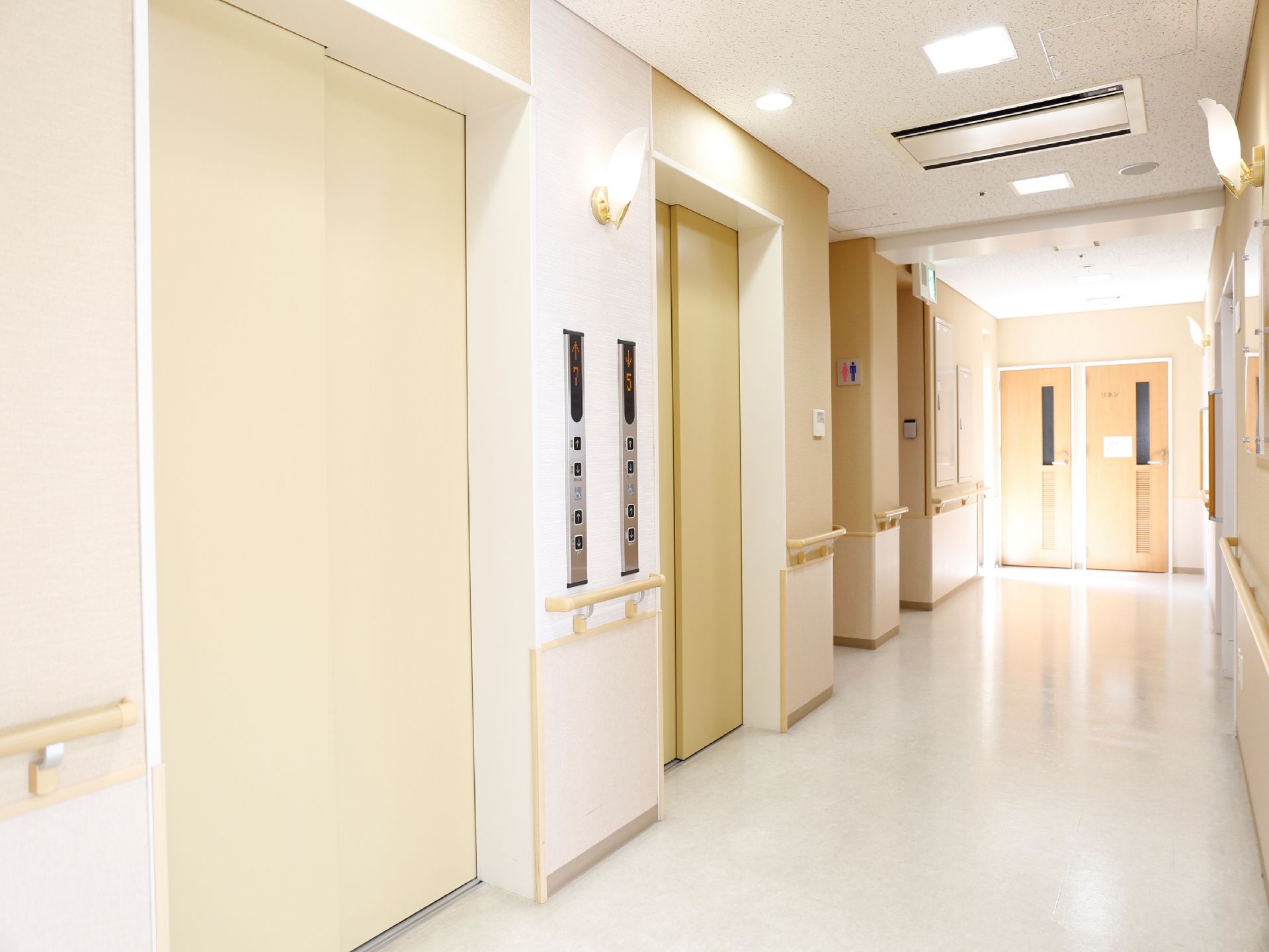 エレベーターが2つ設置されていて、その隣にトイレがある。壁と天井に照明があるので明るい通路である。壁には、手すりが備え付けられている。